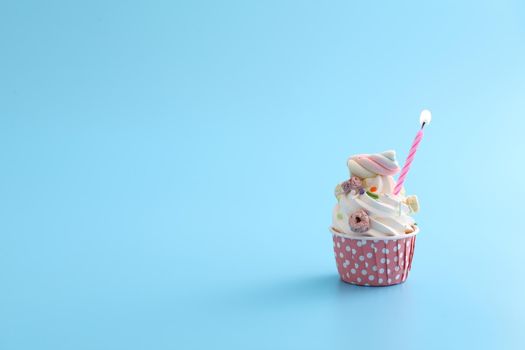 Colorful cupcake with candle isolated in blue background