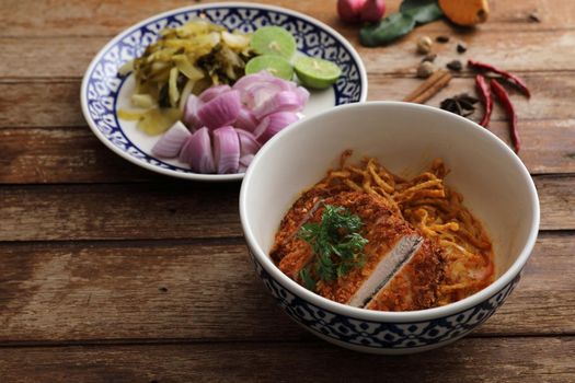 Local northern Thai food Egg noodle curry with fried pork on wood background