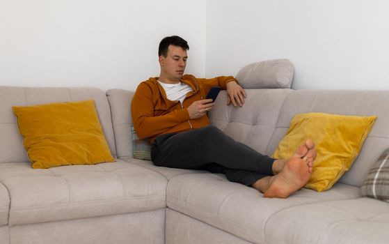 relaxed young man watching at mobile phone on couch. High quality photo