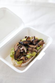 Toast with avocado and grilled mushroom with delivery package in white background