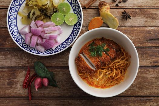 Local northern Thai food Egg noodle curry with fried pork on wood background