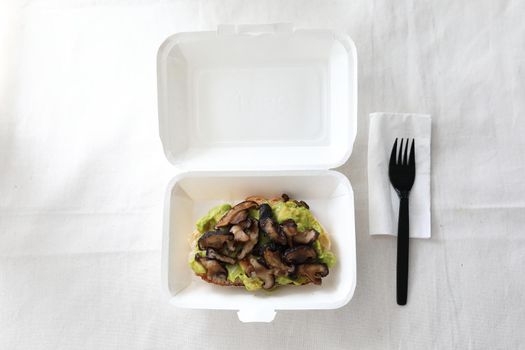 Toast with avocado and grilled mushroom with delivery package in white background