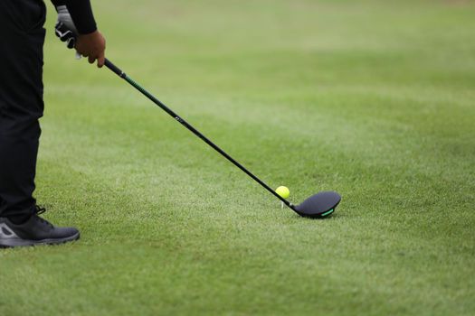 Golf ball on green grass ready to be struck on grass background