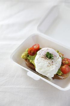 Poached eggs with avocado on toast with delivery package in white background