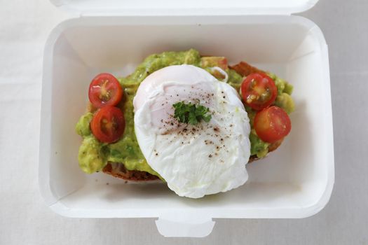 Poached eggs with avocado on toast with delivery package in white background