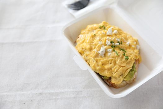 Avocado and scrambled eggs toast with delivery package in white background