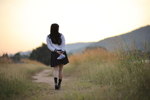 Asian High School Girls student walking in countryside with sunrise