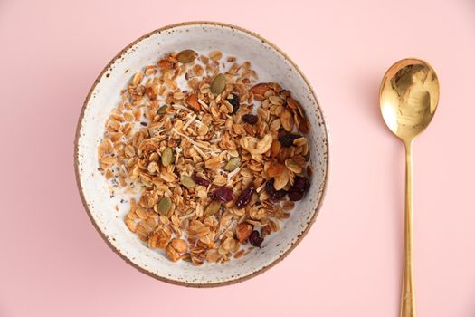 granola with milk with spoon isolated in pink background