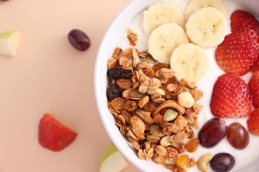 bowl of granola cereal with yogurt and berries isolated on eggnog color background