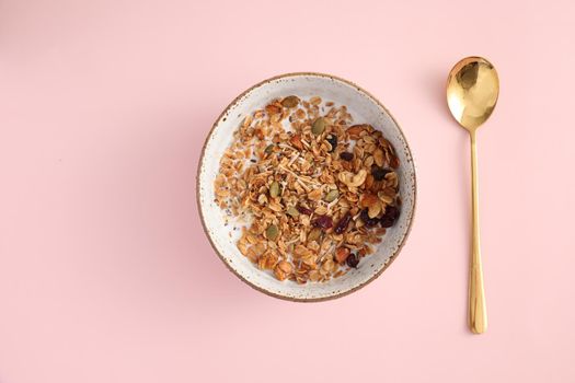 granola with milk with spoon isolated in pink background