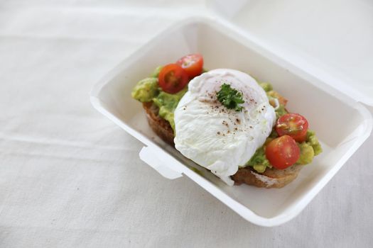 Poached eggs with avocado on toast with delivery package in white background