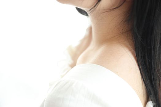 Close up of shoulder young Asian woman on bed relaxing in the morning light with white room