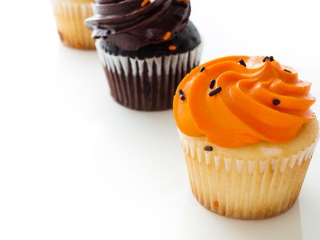 Halloween orange and black cupcakes on white background.