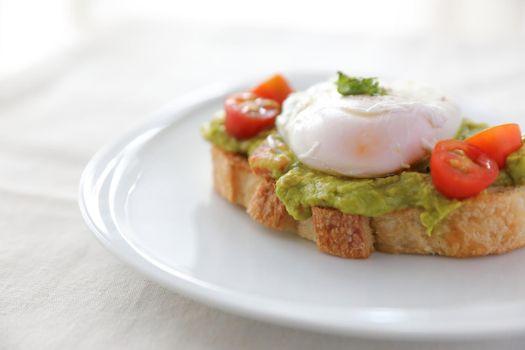 Poached eggs with avocado on toast in white background