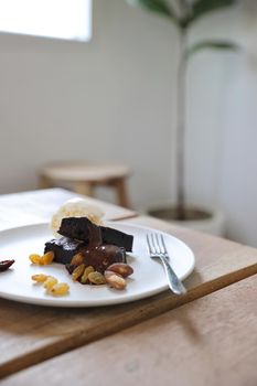 Brownies with dried fruits and ice cream on wood background