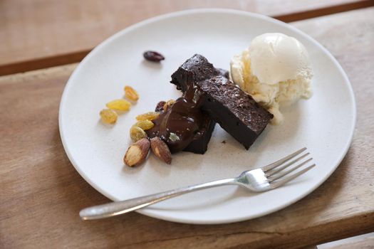 Brownies with dried fruits and ice cream on wood background