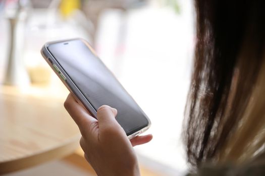 Woman hand using a smartphone for Stock exchange trading online in the coffee shop, business concept