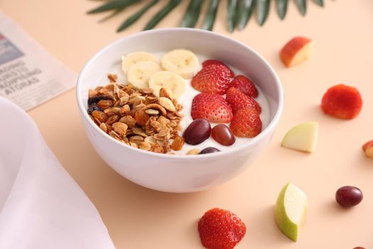 bowl of granola cereal with yogurt and berries isolated on eggnog color background