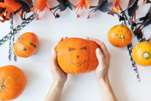 October 31. Halloween holiday. The girl holds the carved face of a pumpkin in her hands. View from above