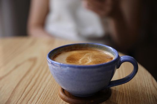 Cappuccino coffee on wood and blur sitting female background