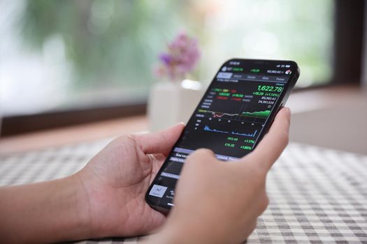 Woman hand using a smartphone for Stock exchange trading online in the coffee shop, business concept