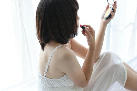 Beautiful young woman makeup cosmetic with brush in white bedroom