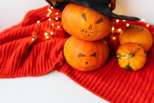 Two pumpkins with a painted face on a red sweater. Holiday concept of October 31, Halloween. Beautiful bokeh on the background