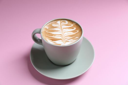 hot cappuccino with latte art isolated in pink background