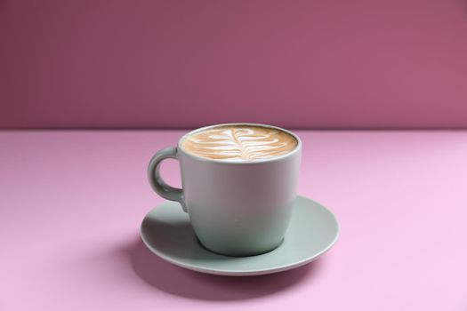 hot cappuccino with latte art isolated in pink background