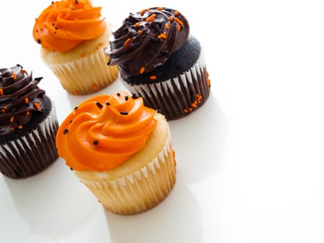 Halloween orange and black cupcakes on white background.