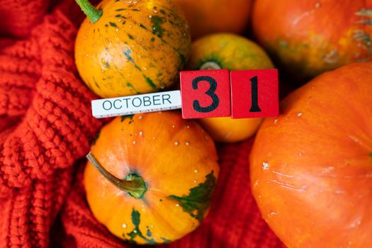 Wooden cube calendar showing October 31st Halloween preparing pumpkins for carving. Holiday and party concept