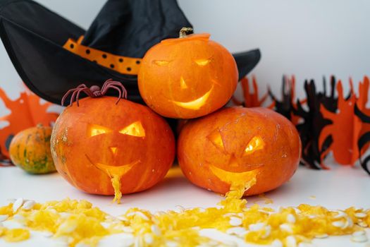 October 31. Holiday Halloween. Carved face of a pumpkin on an orange-black background. Hat, spider, lights, glows