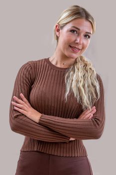 26-year-old woman smiling, her arms crossed on a gray background.