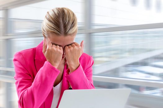 Young woman facing her computer, exhausted fists against her eyes