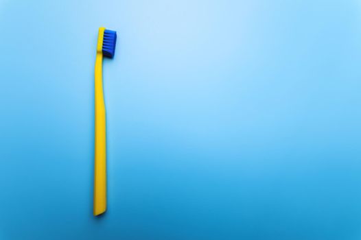 top view close-up of a bright toothbrush, alone, without people, lies on a blue background.