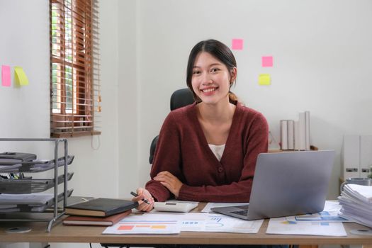 Portrait of an Asian young business Female working on a laptop computer in her workstation.Business people employee freelance online report marketing e-commerce telemarketing concept..