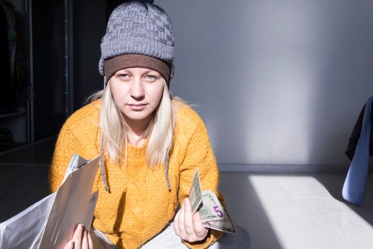 A young girl in a yellow sweater and two hats is horrified to study large bills, taxes and utility bills..