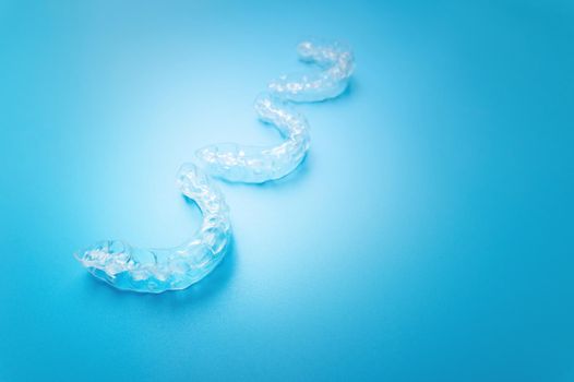 close-up, new transparent braces lie in a row on a blue background. suitable for dental clinic banner.