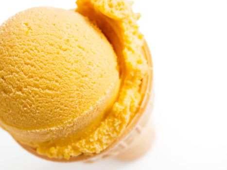 Scoop of gourmet pumpkin gelato in cake cone on white background.