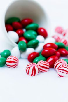Christmas candies spilled out of the cup on white background.