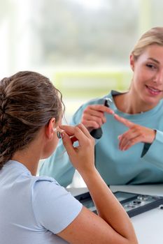 Woman in front of a hearing care professional to test a hearing aid.