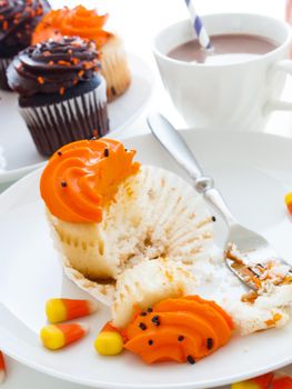 Eating Halloween cupcakes with orange and black icing.