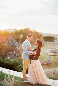 Groom holds bride by the forearms while standing on a stone path in the mountains. High quality photo