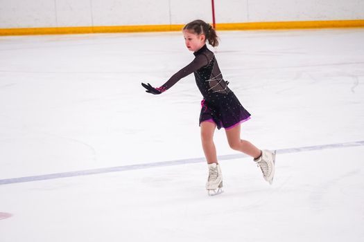 Little girl practicing before her figure skating competition at the indoor ice rink.