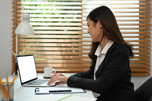 Asian businesswoman working with laptop computer and financial document at her workplace.