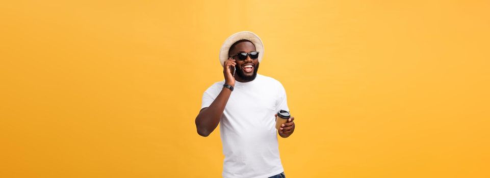 Handsome African American with mobile phone and take away coffee cup. Isolated over yellow gold background