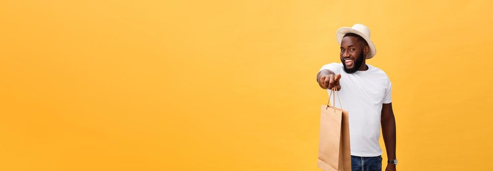 African American man with colorful paper bags isolated on yellow background.