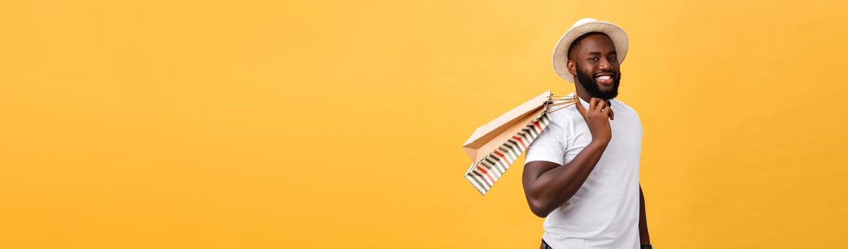 African American man with colorful paper bags isolated on yellow background.