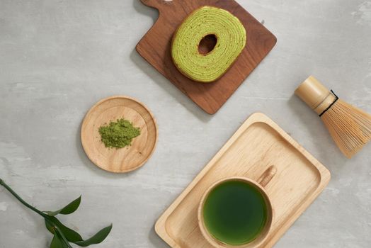 Green tea matcha in a wooden cup with German cake on the brown mat close-up