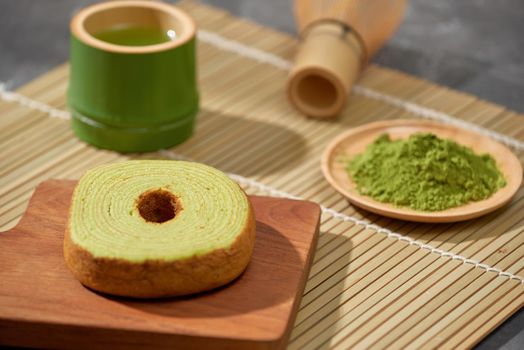 Matcha green tea latte in a cup and tea ceremony utensils with German cake. Copy space